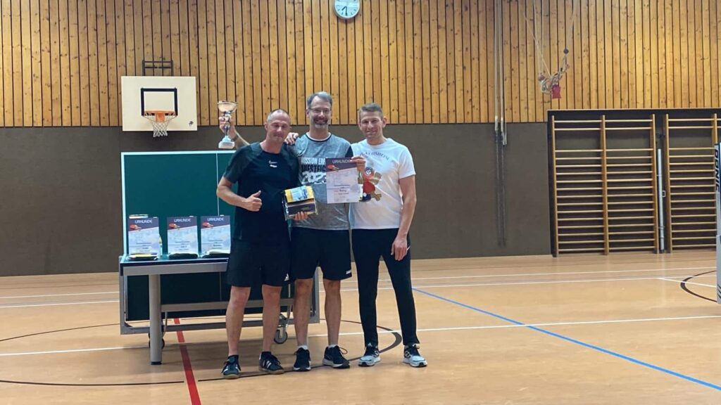 a group of men standing in a gym holding a trophy