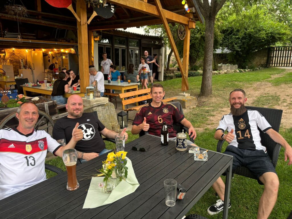 a group of men sitting at a table with drinks and a wooden structure