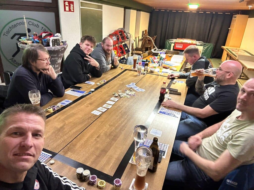 a group of men sitting around a table with cards and beer