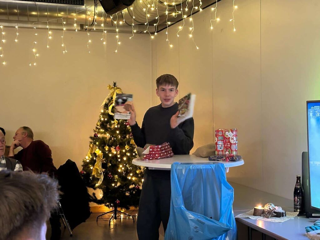 a boy holding books in front of a christmas tree