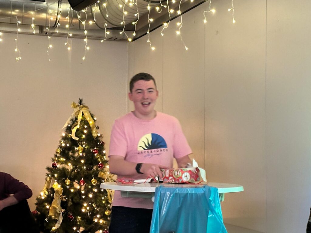 a man standing at a table with a christmas tree and lights