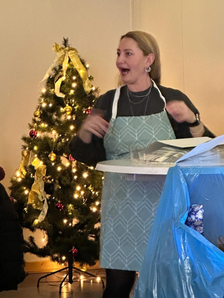 a woman in an apron standing in front of a christmas tree